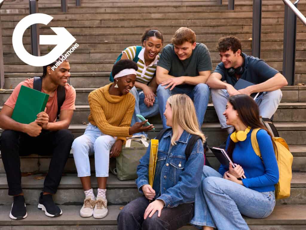 Group of diverse students sitting on stairs, studying and chatting outdoors.